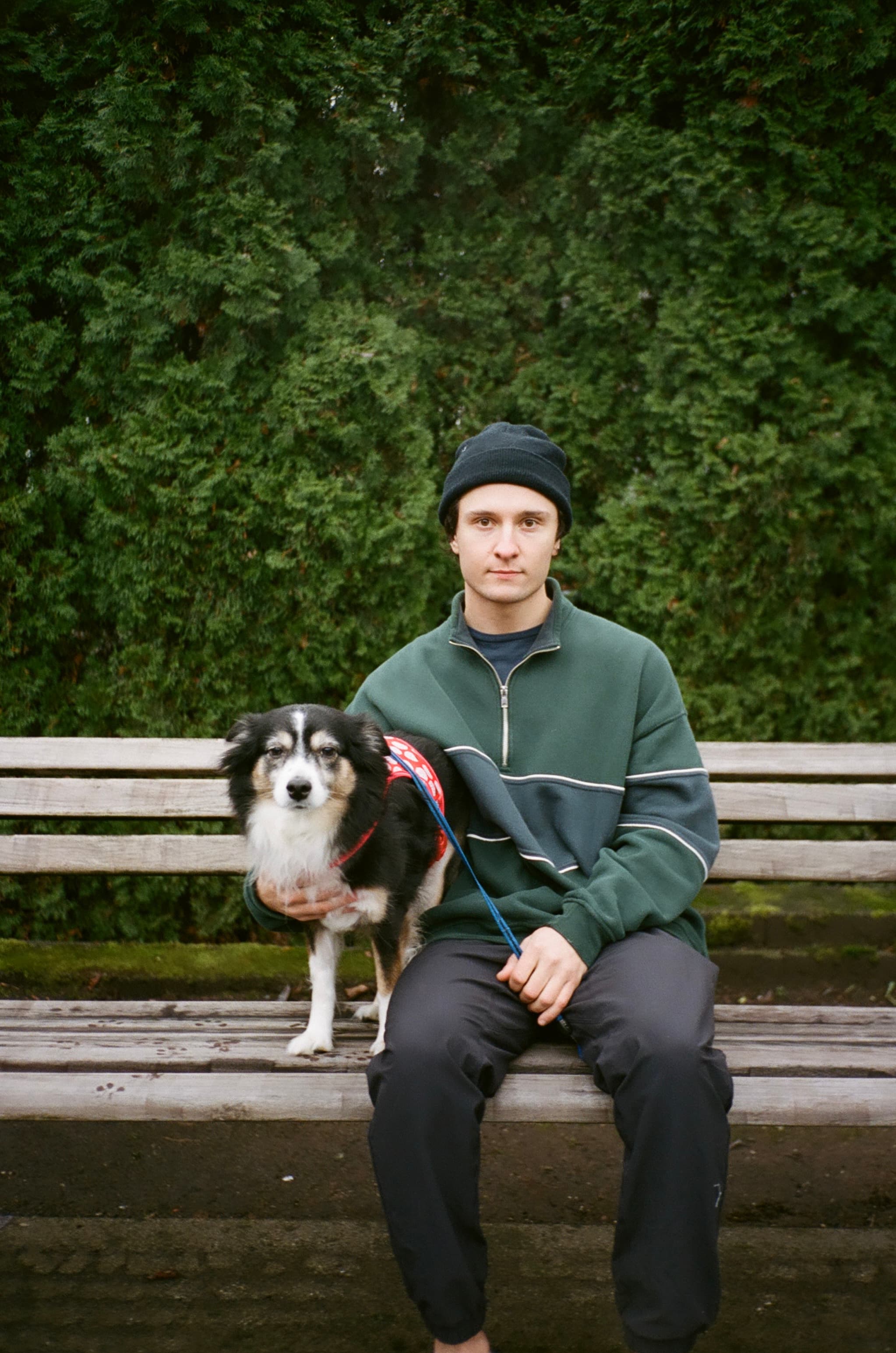 Tomasz sitting on a park bench with his dog on a leash.
