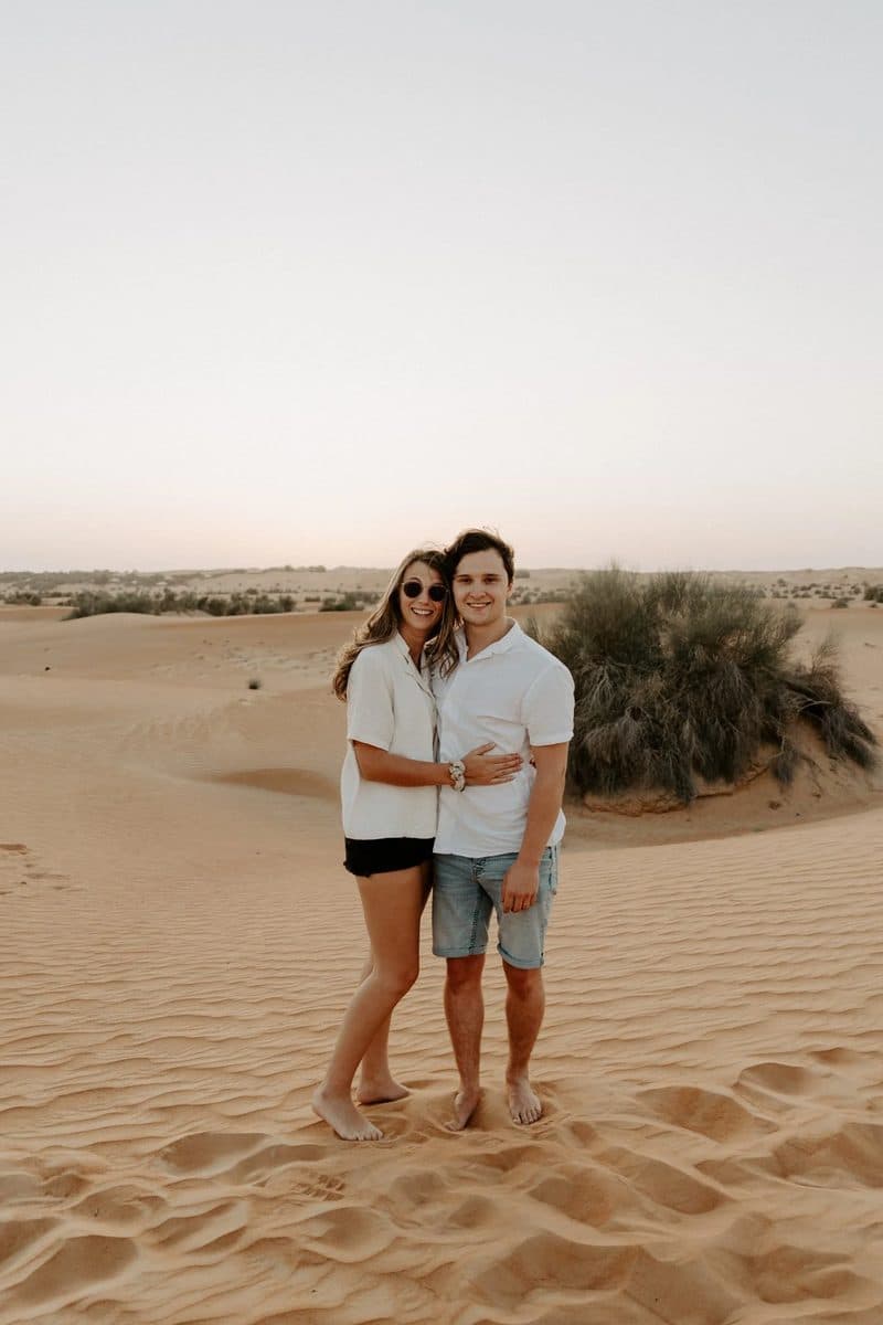 Simone and Tomasz standing together on desert sand dunes at dusk.